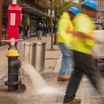 A fire hydrant open with water pouring out; being flushed